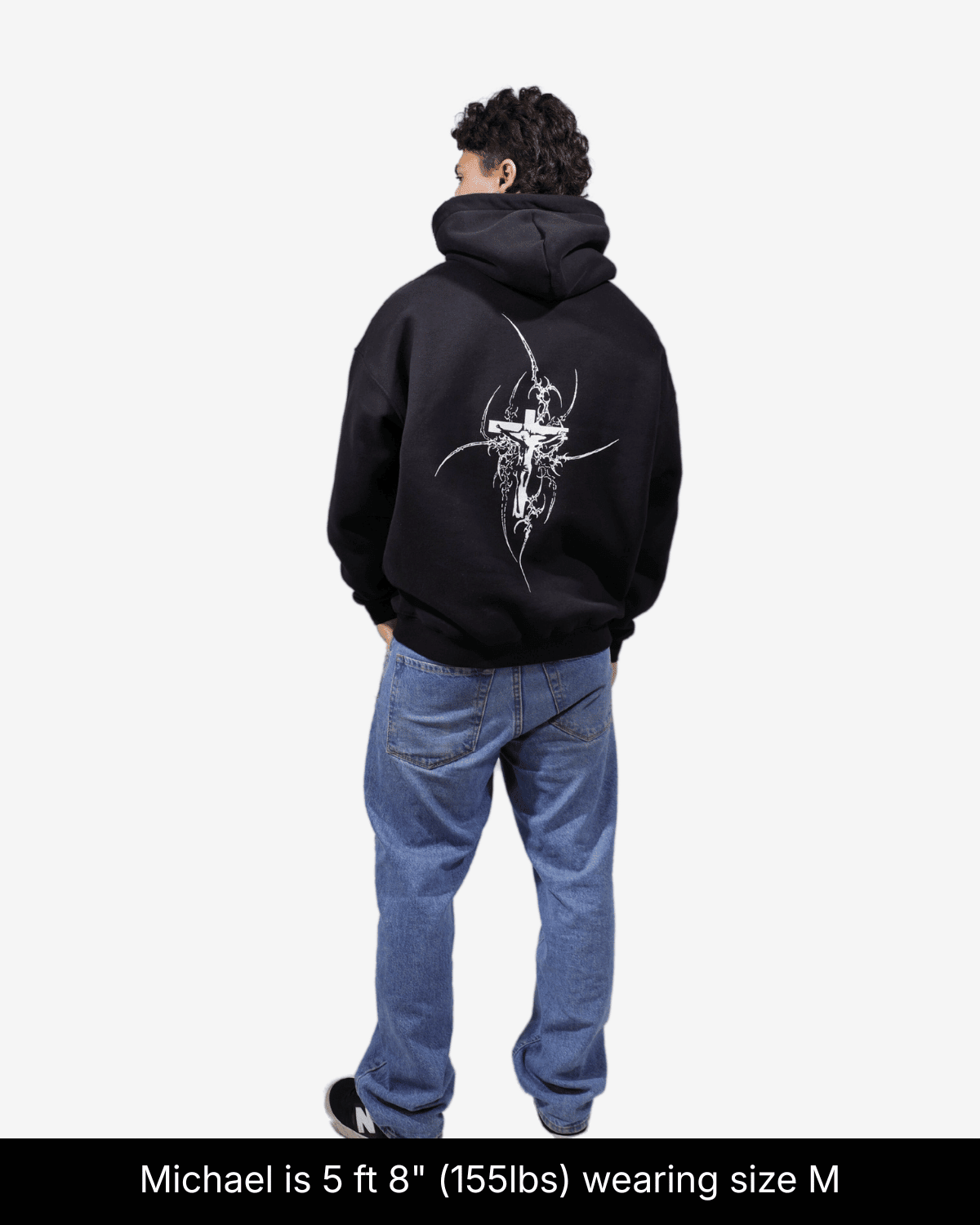 Model wearing black Eternal Life hoodie, showing a white cross graphic on the back in size M.