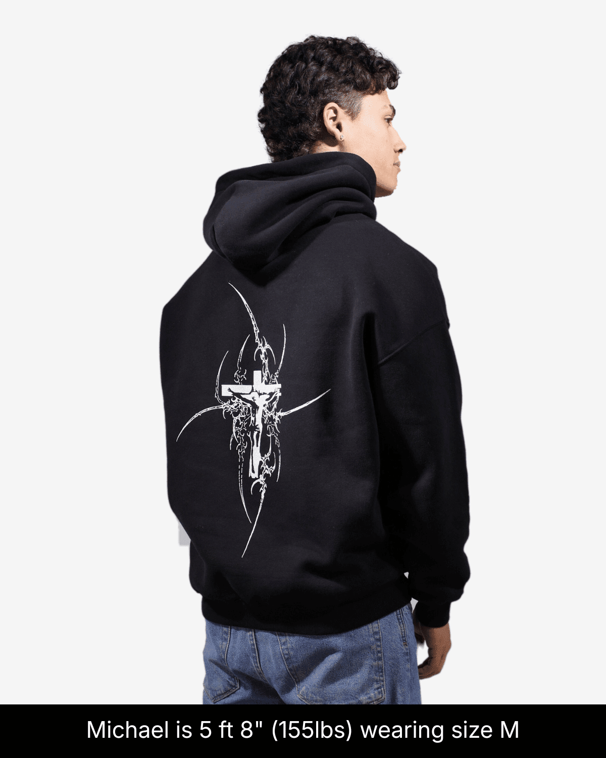 Close-up of a model wearing the black Eternal Life hoodie in size M, showing the cross back print.