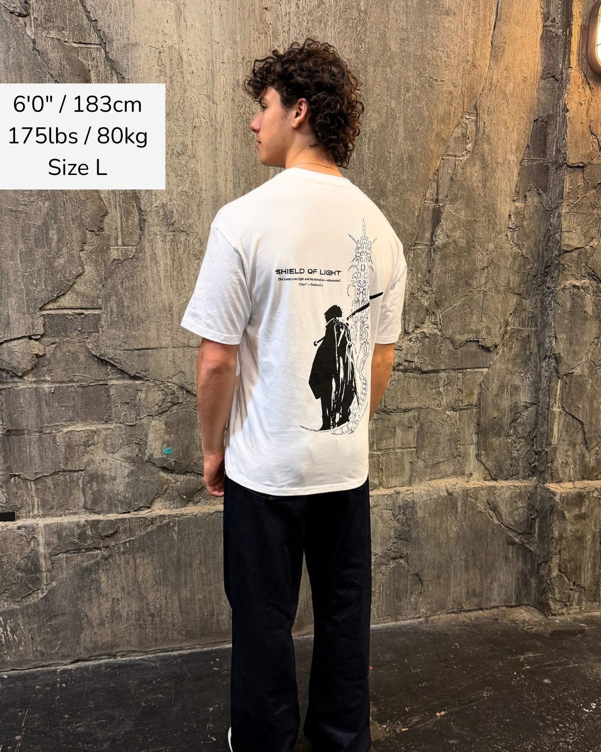 Shield Of Light faith based t-shirt white back design worn by model outdoor setting
