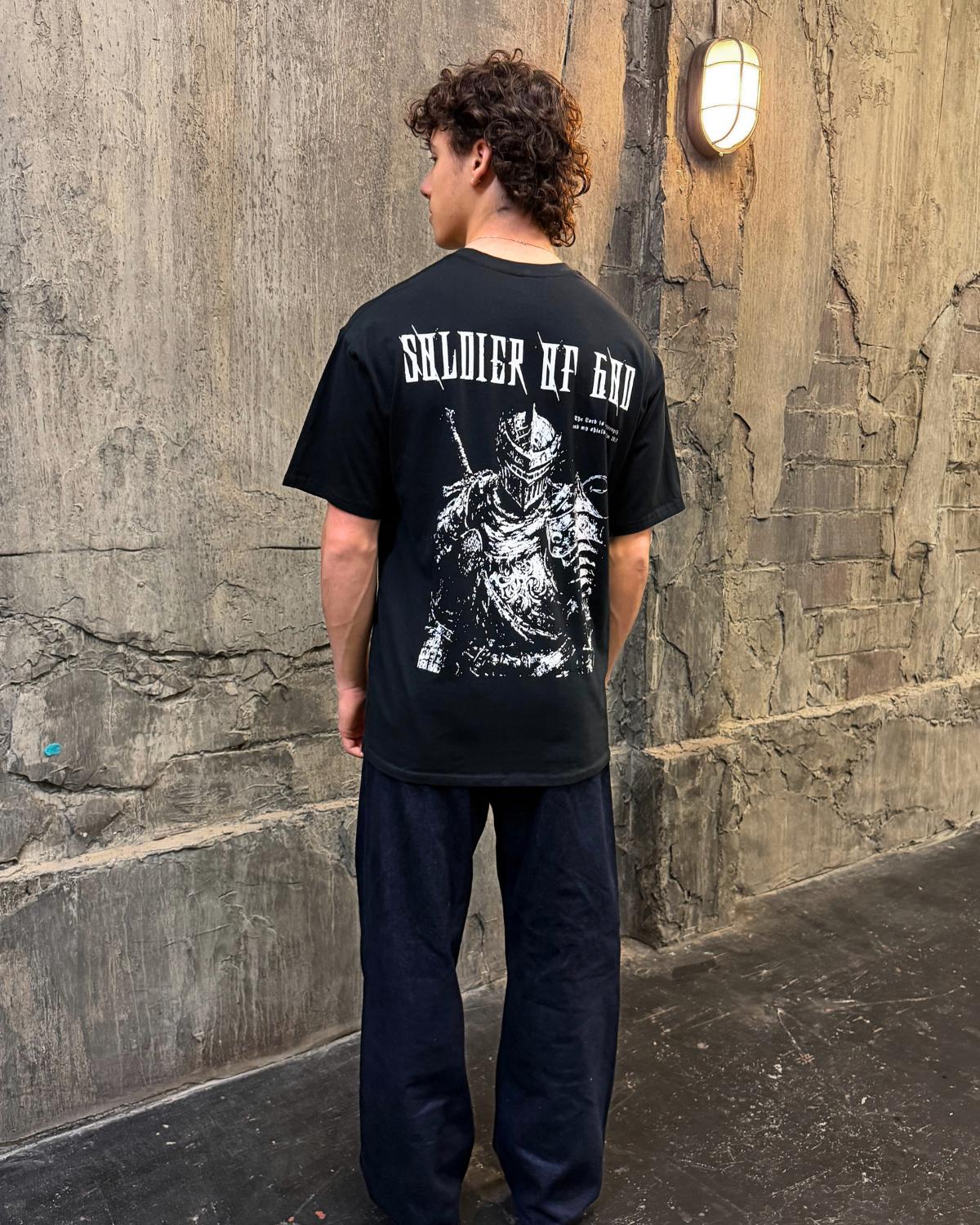 Soldier Of God faith based t-shirt black back graphic worn by model outdoor wall